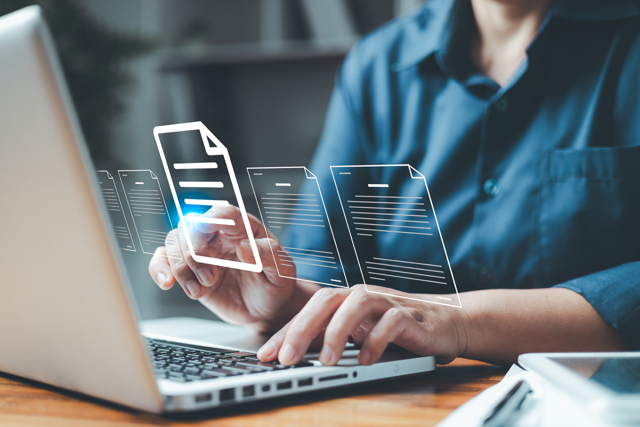 Person working on a laptop with fly out icons of documents.