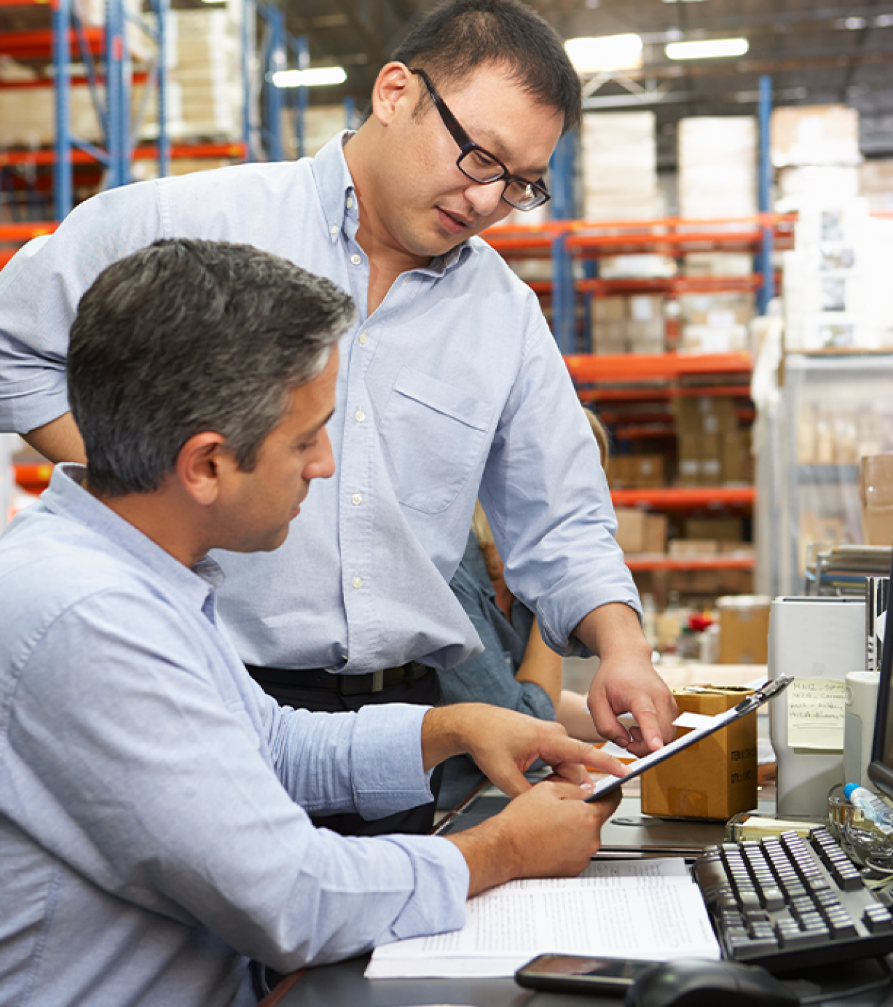 Two men discussing items in a warehouse.