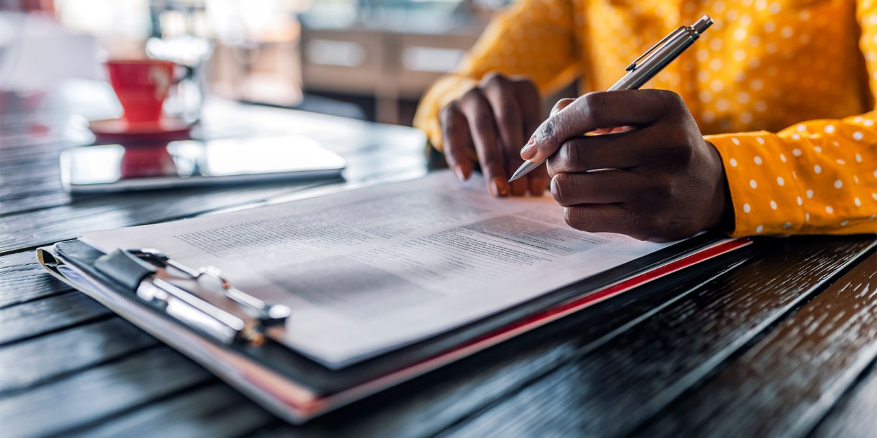 Person filling in documentation holding a pen.